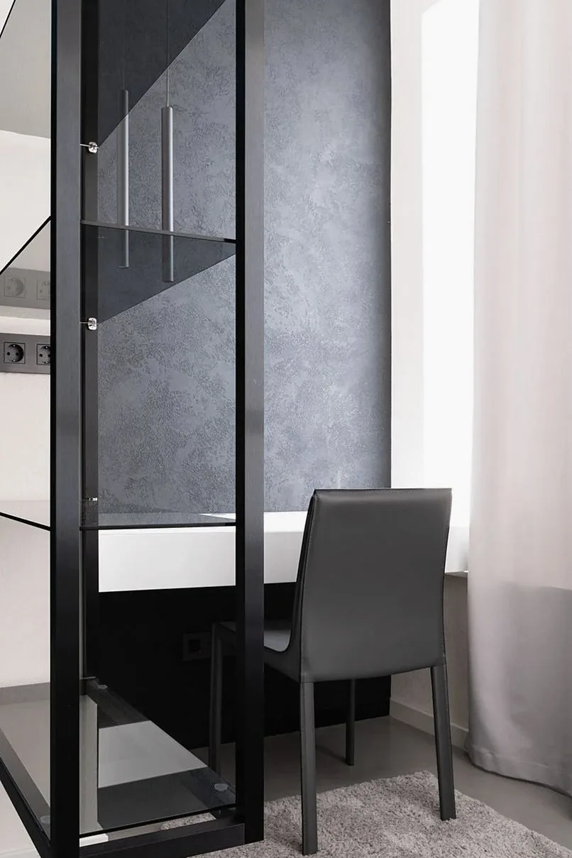 Black-framed glass partition beside a dark chair