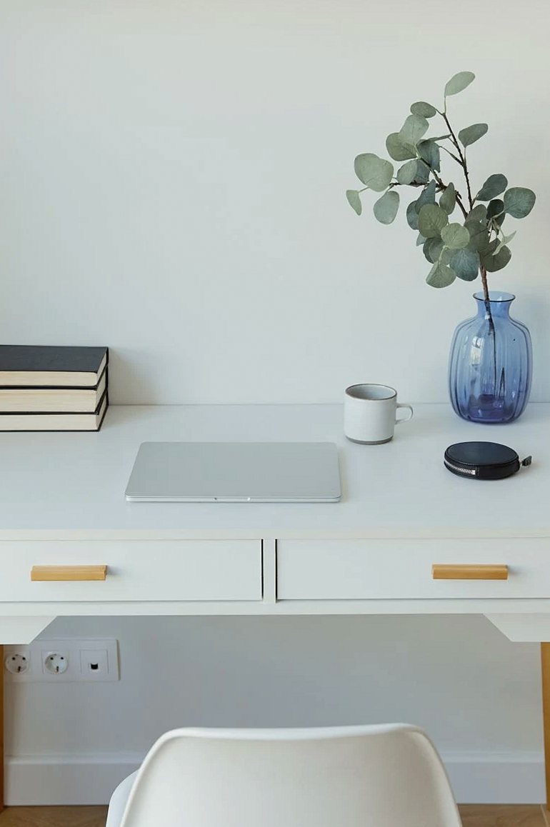 White desk with a vase, books and a mug